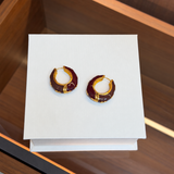 Vintage burgundy enamel hoop earrings displayed on a white box