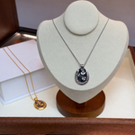 Black and silver clover pendant necklace on display bust