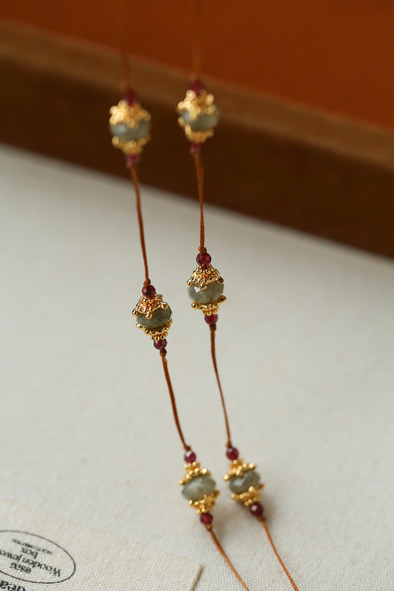 Close-up of gemstone stations on brown cord