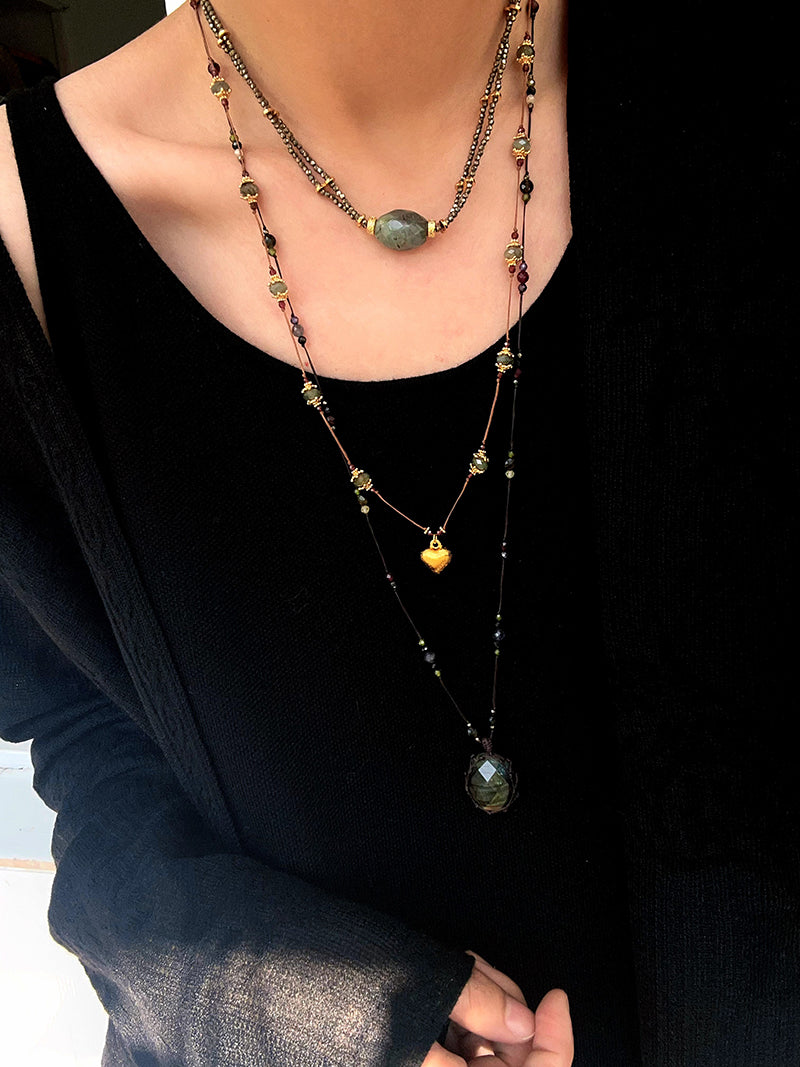Long heart pendant necklace layered with shorter necklaces