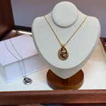 Burgundy and gold clover pendant necklace on display bust