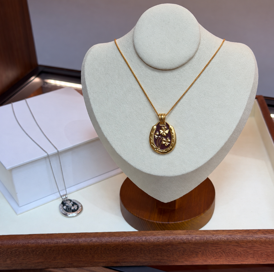 Burgundy and gold clover pendant necklace on display bust