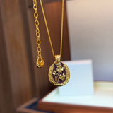 Burgundy and gold four-leaf clover pendant necklace - close-up