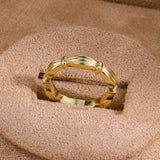 Gold ribbon-inspired band ring on display