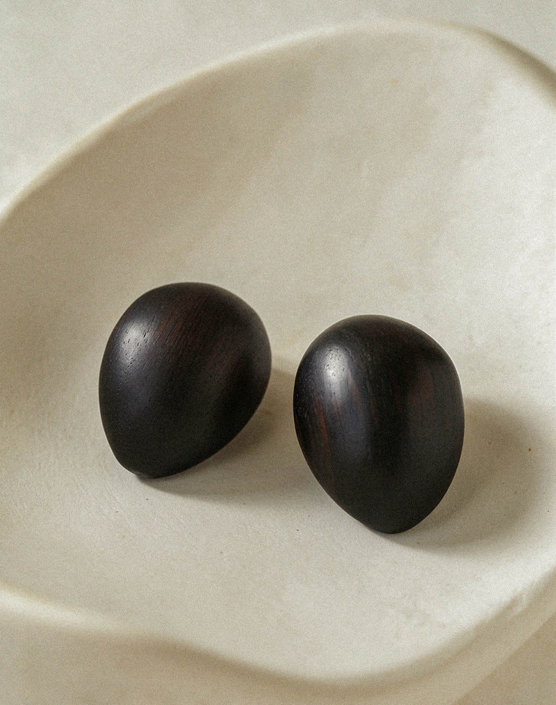 Ebony wood oval earrings resting in a cream ceramic dish