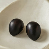 Ebony wood oval earrings resting in a cream ceramic dish