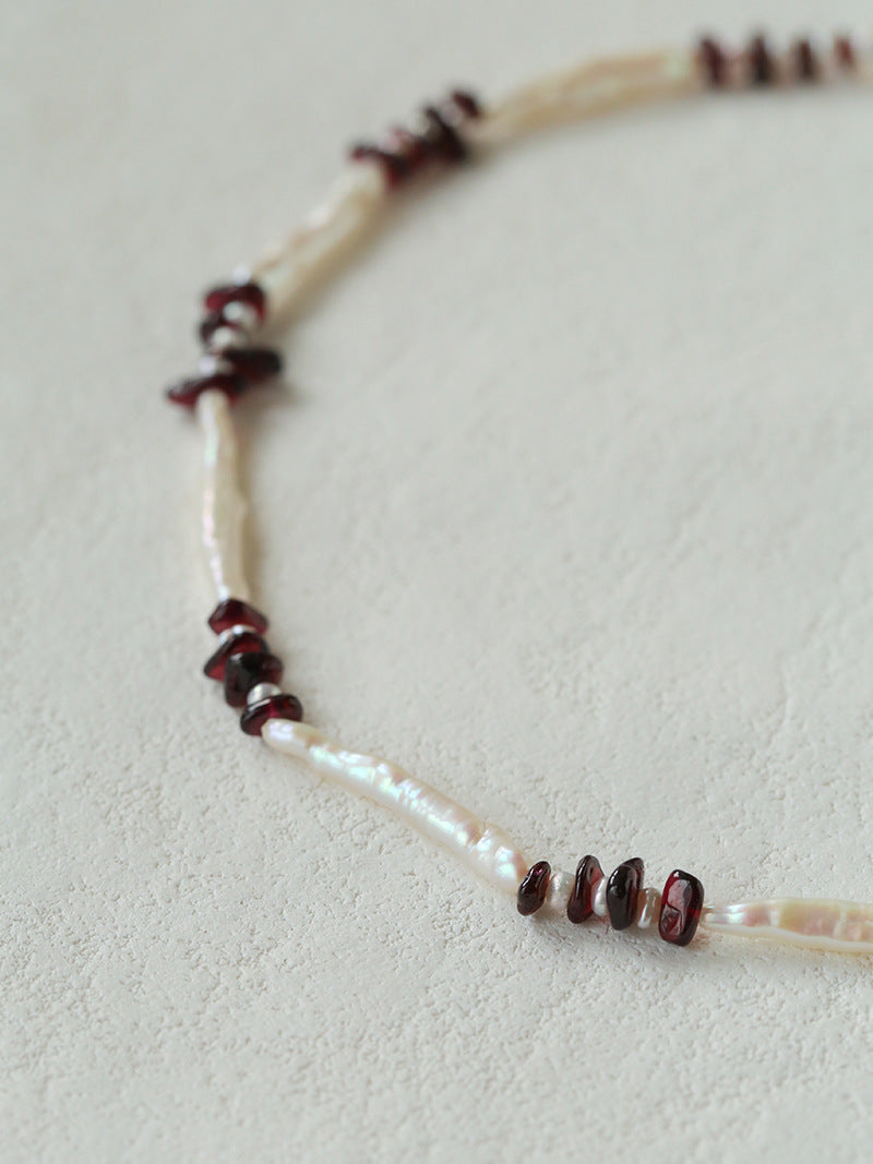 Close-up comparing elongated and small freshwater pearls with garnet chips