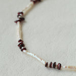 Close-up comparing elongated and small freshwater pearls with garnet chips