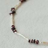 Close-up comparing elongated and small freshwater pearls with garnet chips