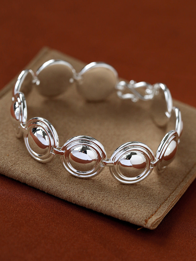 Silver oval dome bracelet on a brown display