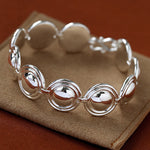 Silver oval dome bracelet on a brown display