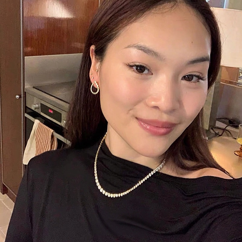 Gold tennis necklace worn with a black top