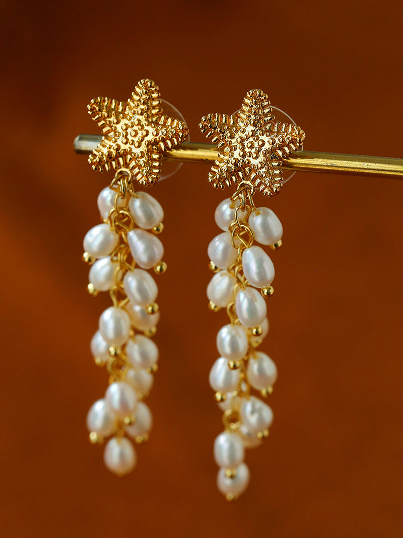Starfish freshwater pearl tassel earrings hanging from a display