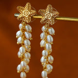 Starfish freshwater pearl tassel earrings hanging from a display