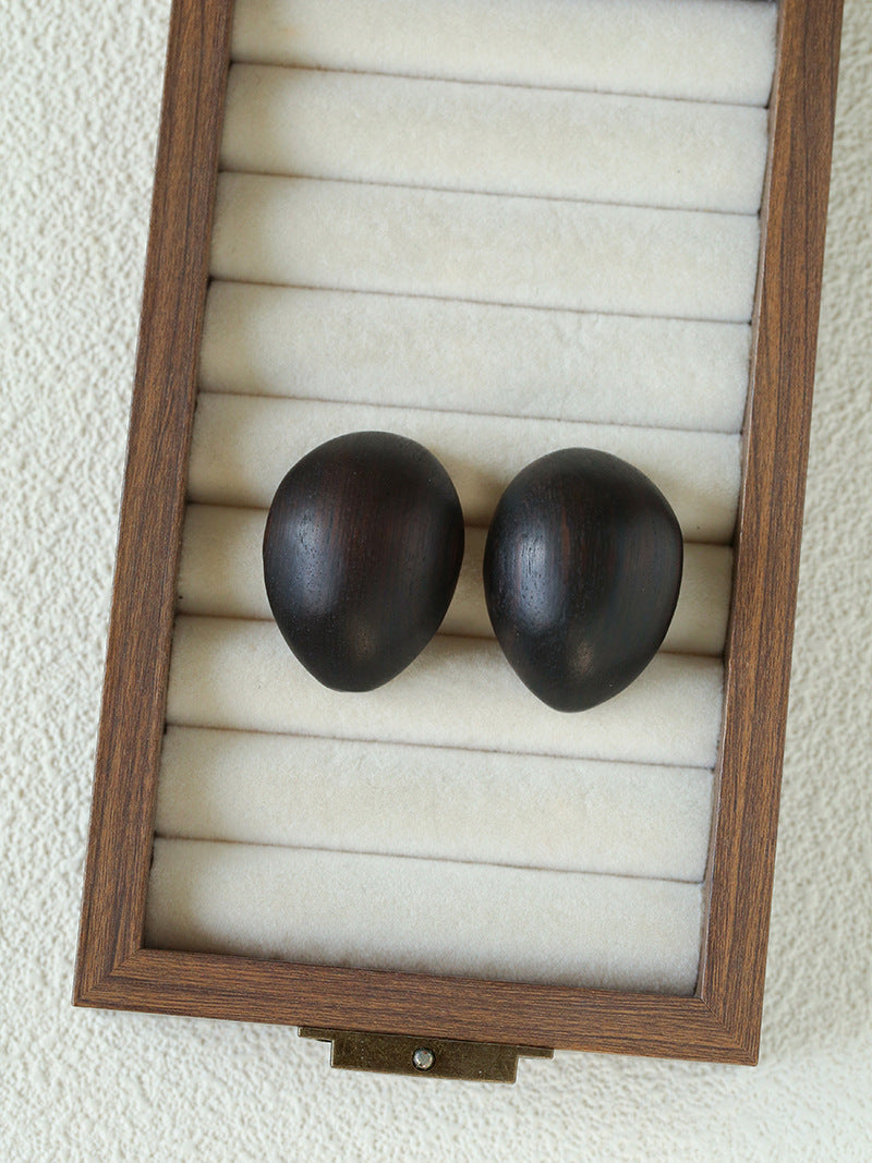 Pair of ebony wood statement earrings in a wooden jewellery tray