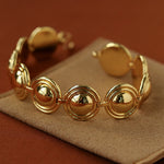 Gold oval dome bracelet on a brown display
