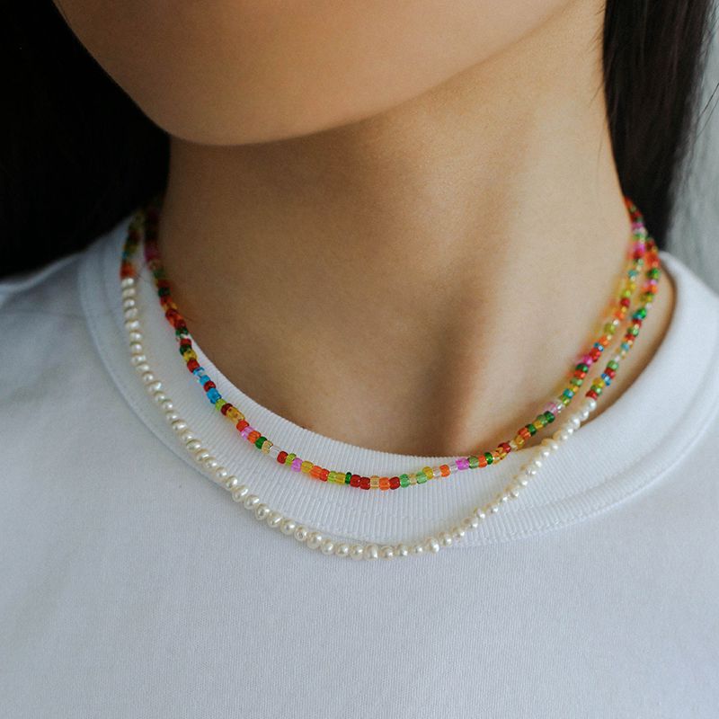 Colourful glass bead and freshwater pearl necklaces worn as a layered set
