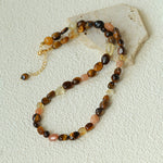 Natural stone necklace with warm brown and peach beads arranged in a loop