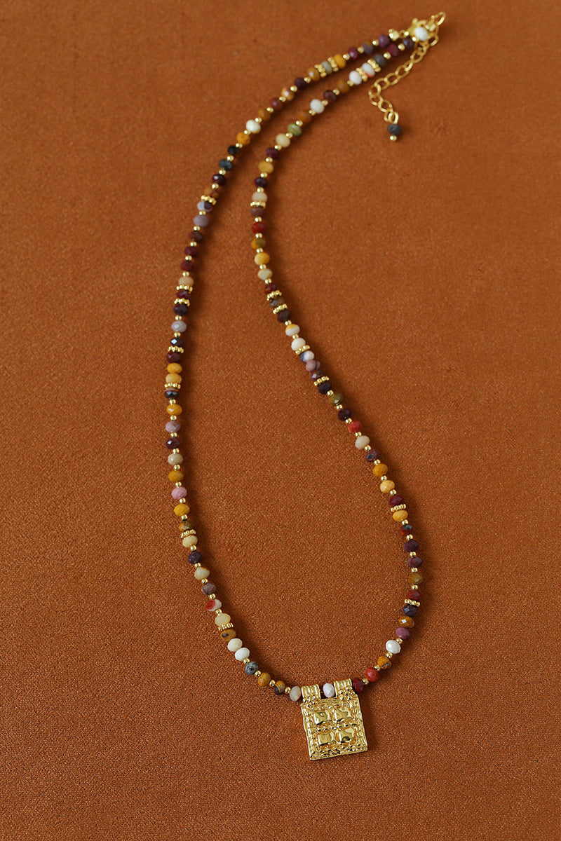 Multicolor natural stone necklace arranged on brown fabric