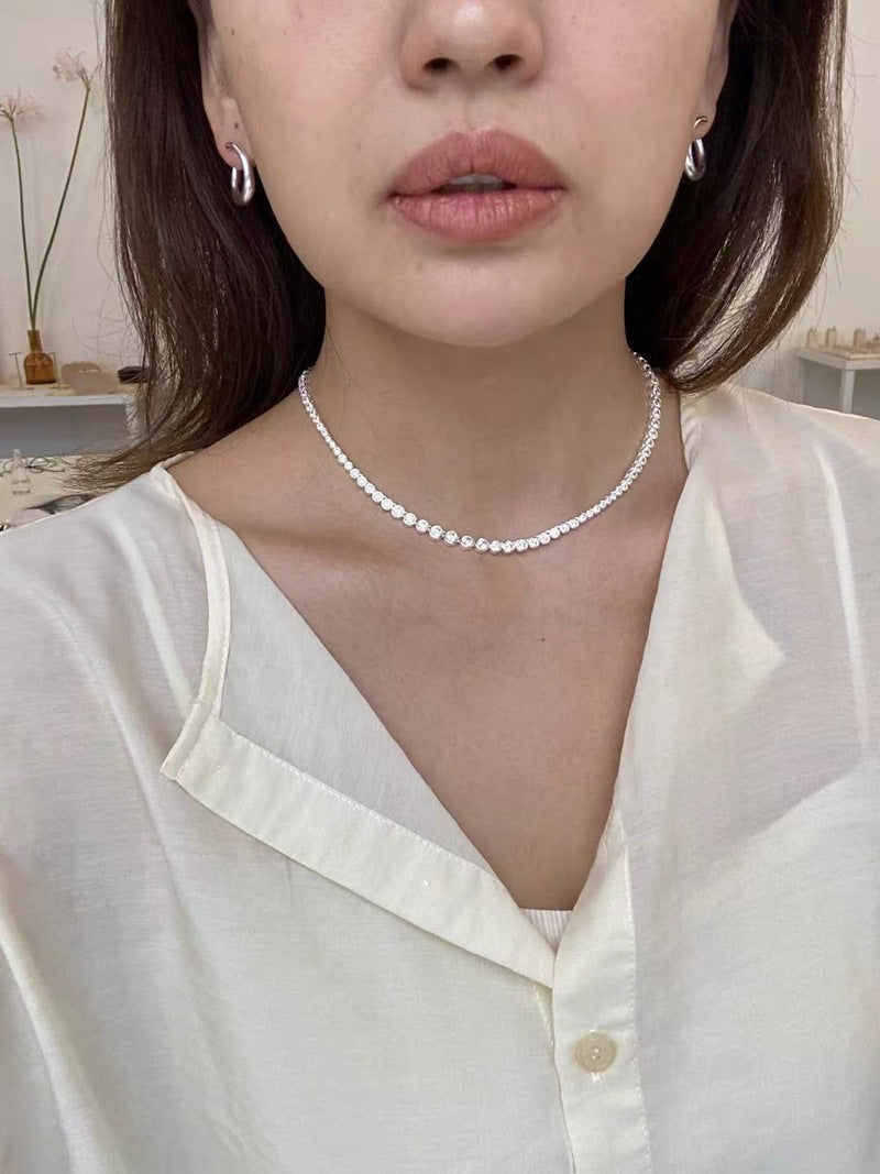 Silver graduated CZ tennis necklace worn with a white blouse