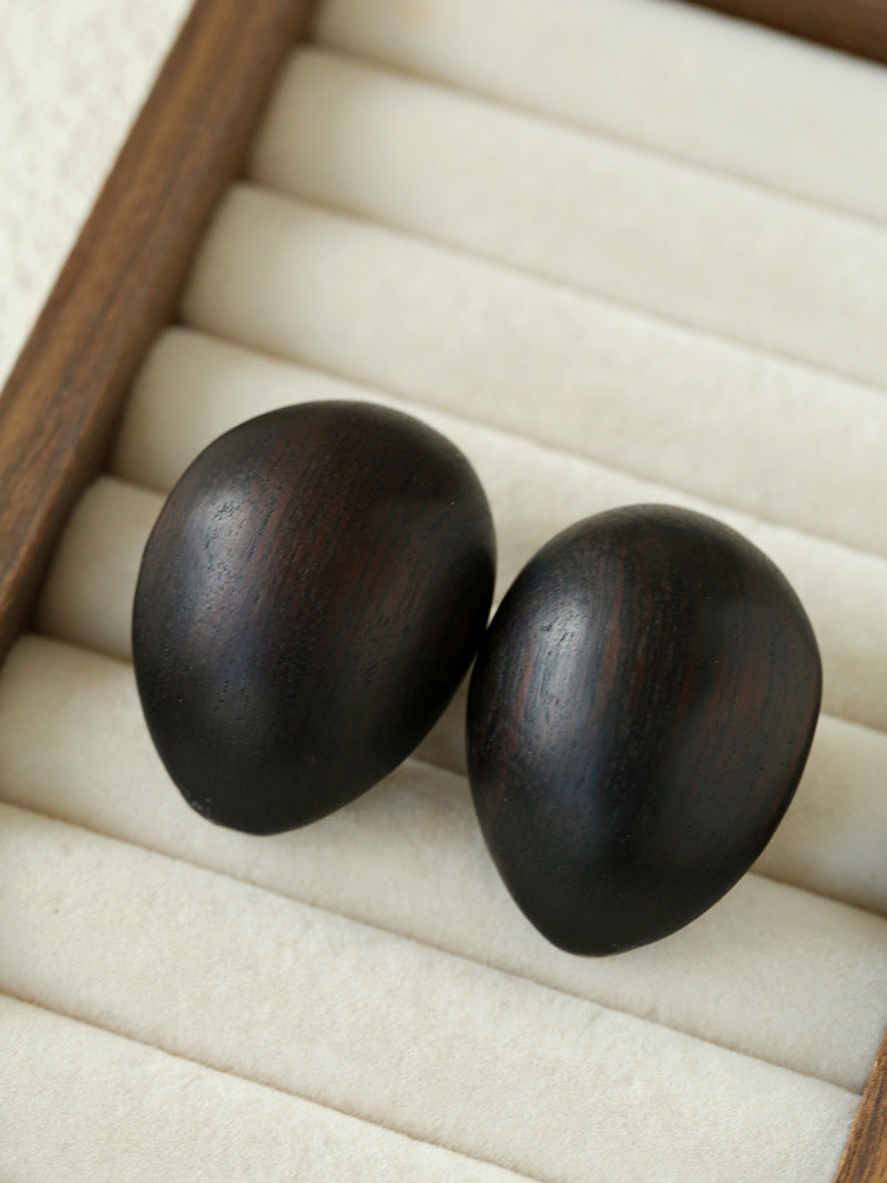 Front view of ebony wood oval earrings in a cream jewellery tray