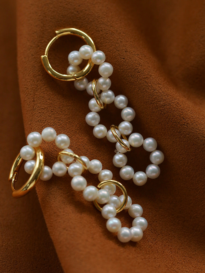 Angled view of interlocking pearl circles and gold-tone hoop fastenings