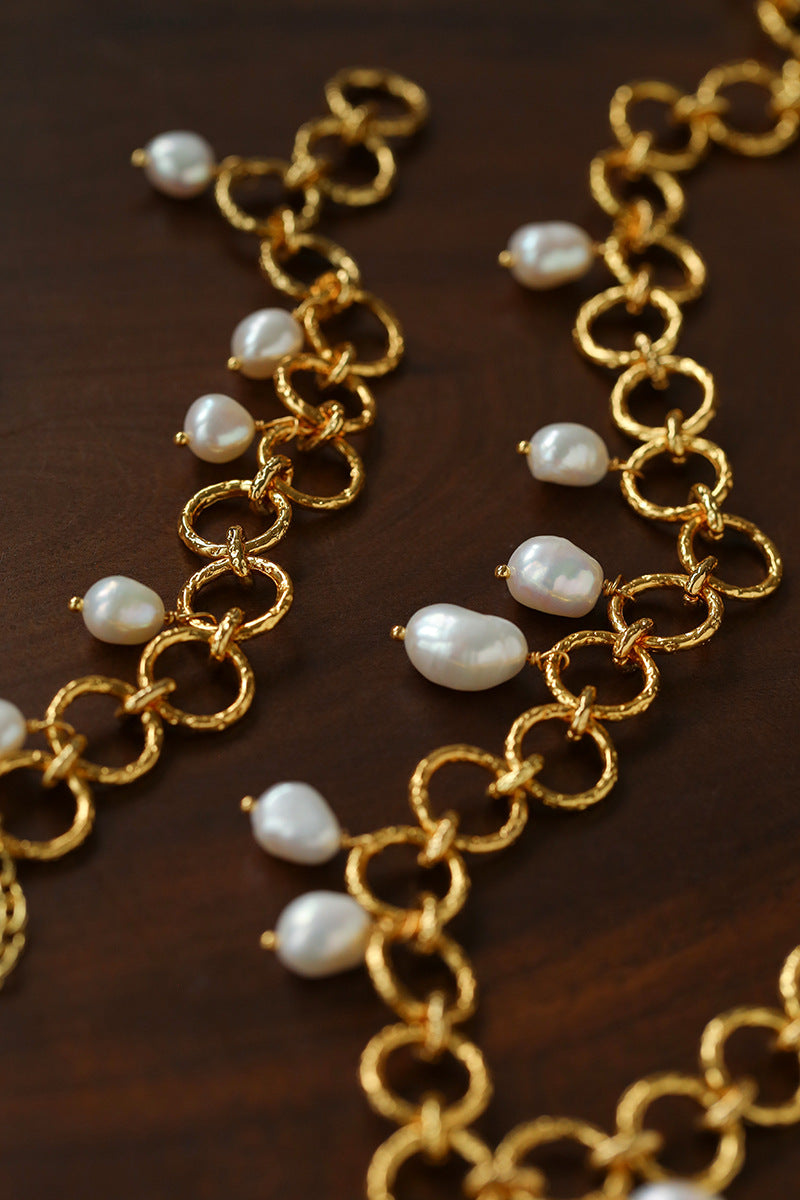 Close-up of textured gold circle links and freshwater pearl charms