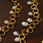 Close-up of textured gold circle links and freshwater pearl charms