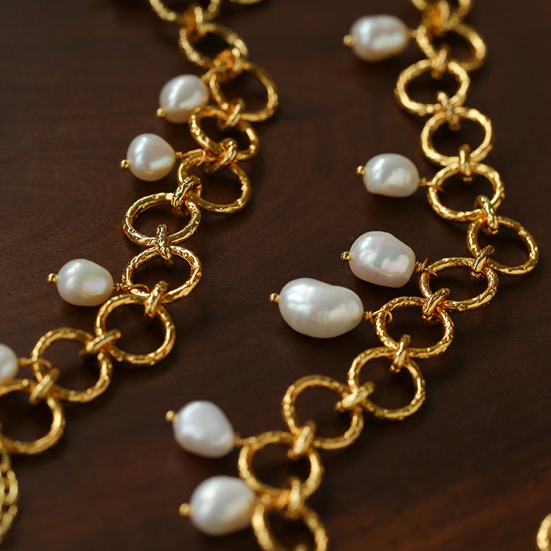 Close-up of textured gold circle links and freshwater pearl charms