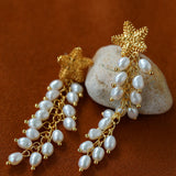 Angled view of gold starfish and pearl tassel earrings
