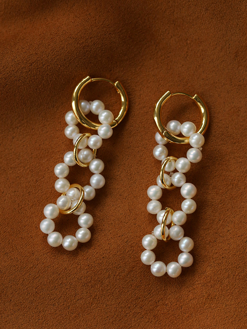 Large pearl hoop drop earrings arranged on brown fabric