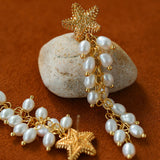 Starfish pearl tassel earrings arranged beside a stone