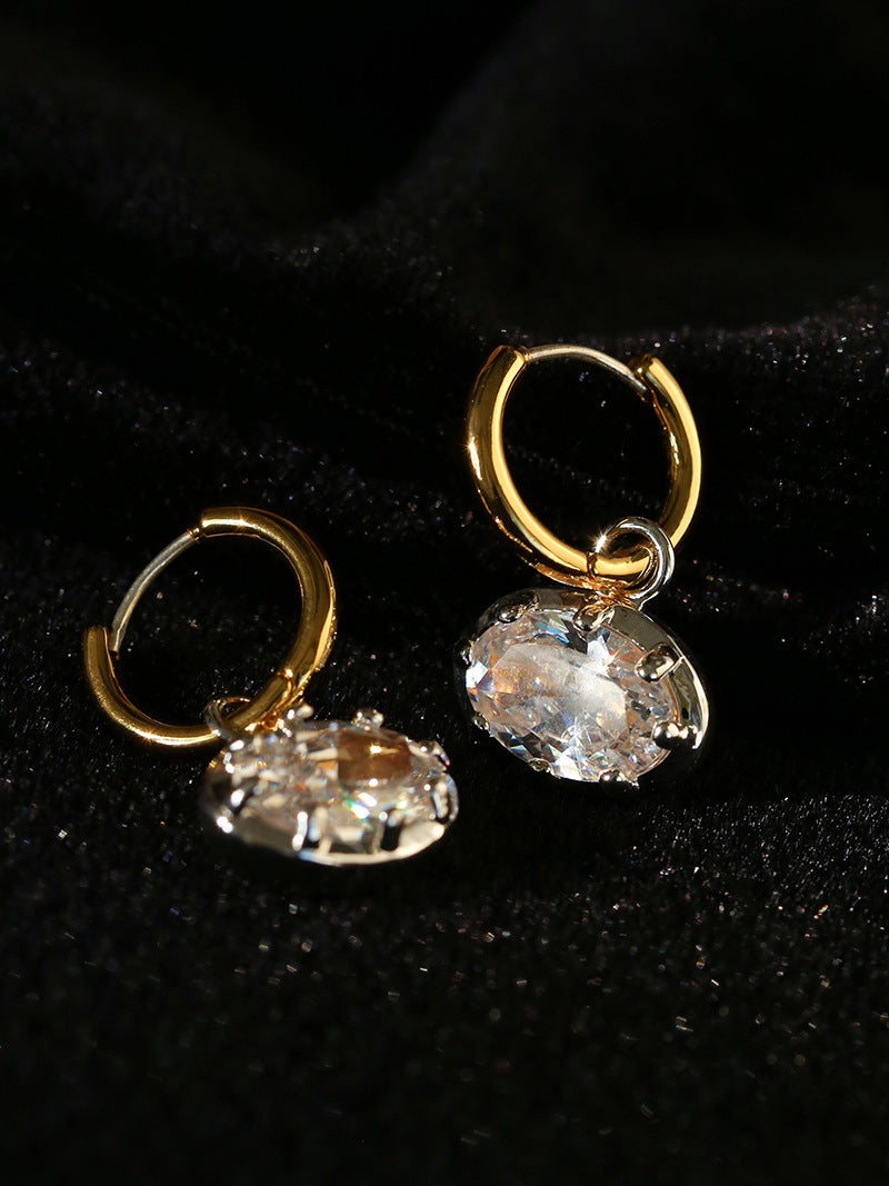 Side view of oval cubic zirconia drops suspended from hinged gold hoops