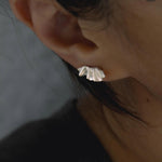 Close-up of silver ruffle stud earring worn on the ear
