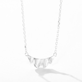 Silver ruffle pendant and chain on white background