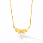Gold ruffle pendant and chain on white background