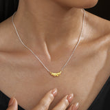 Two-tone ruffle pendant necklace worn at the neckline