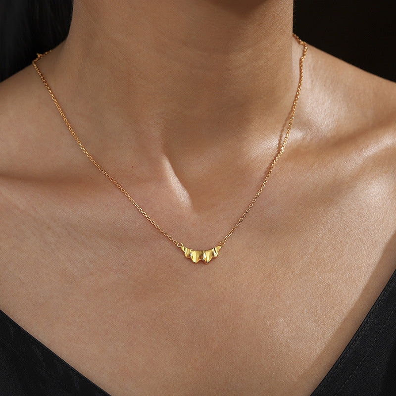 Gold ruffle pendant necklace worn at the neckline