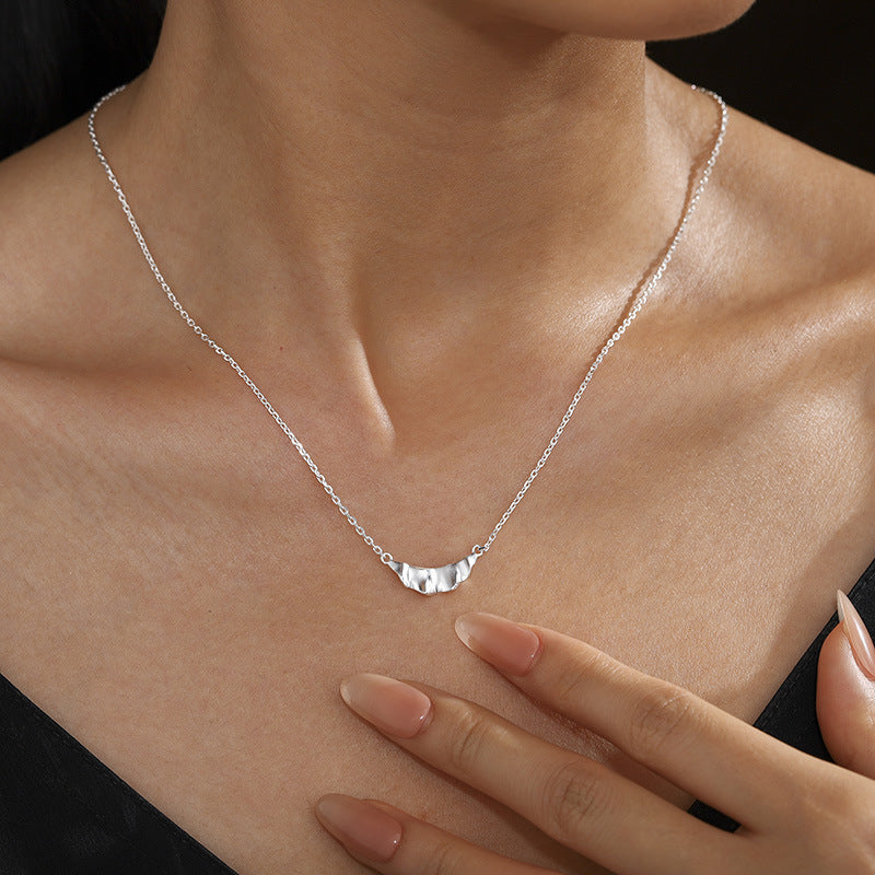 Silver ruffle pendant necklace worn at the neckline