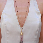 Long graduated gemstone tassel necklace worn with a white halter top