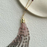Pink and grey gemstone tassel spread beneath a gold-tone cap
