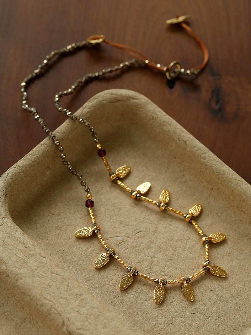 Close-up of faceted pyrite beads and textured leaf charms