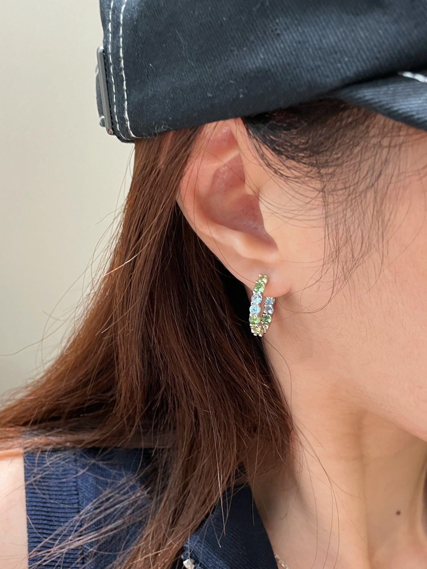 Colourful green and blue gradient hoop earrings worn on the ear