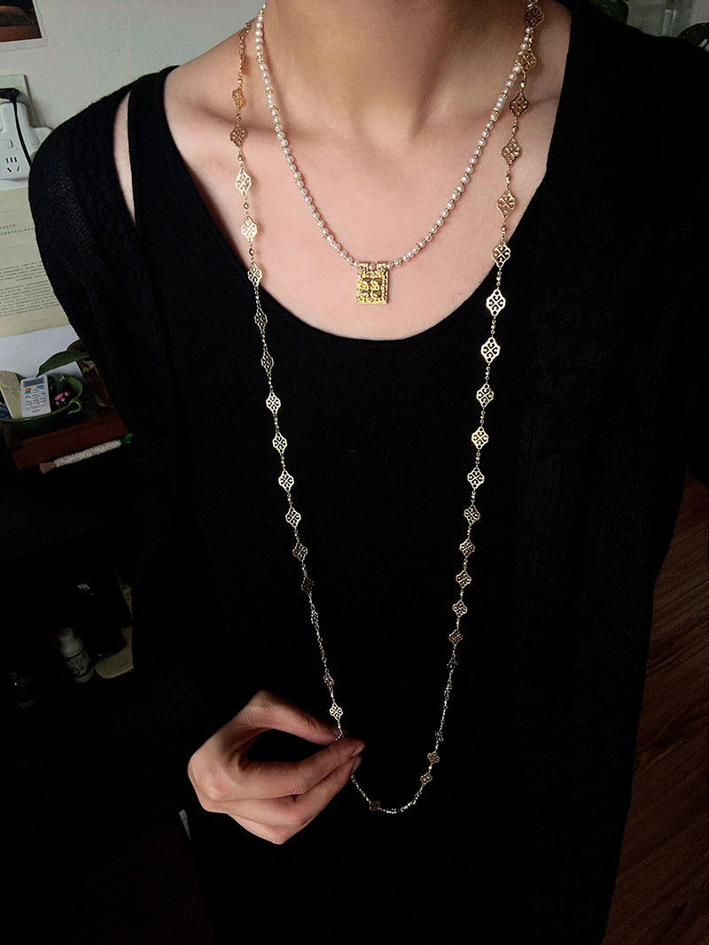 Square pendant necklace layered with longer necklaces