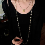 Square pendant necklace layered with longer necklaces