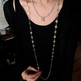 Square pendant necklace layered with longer necklaces