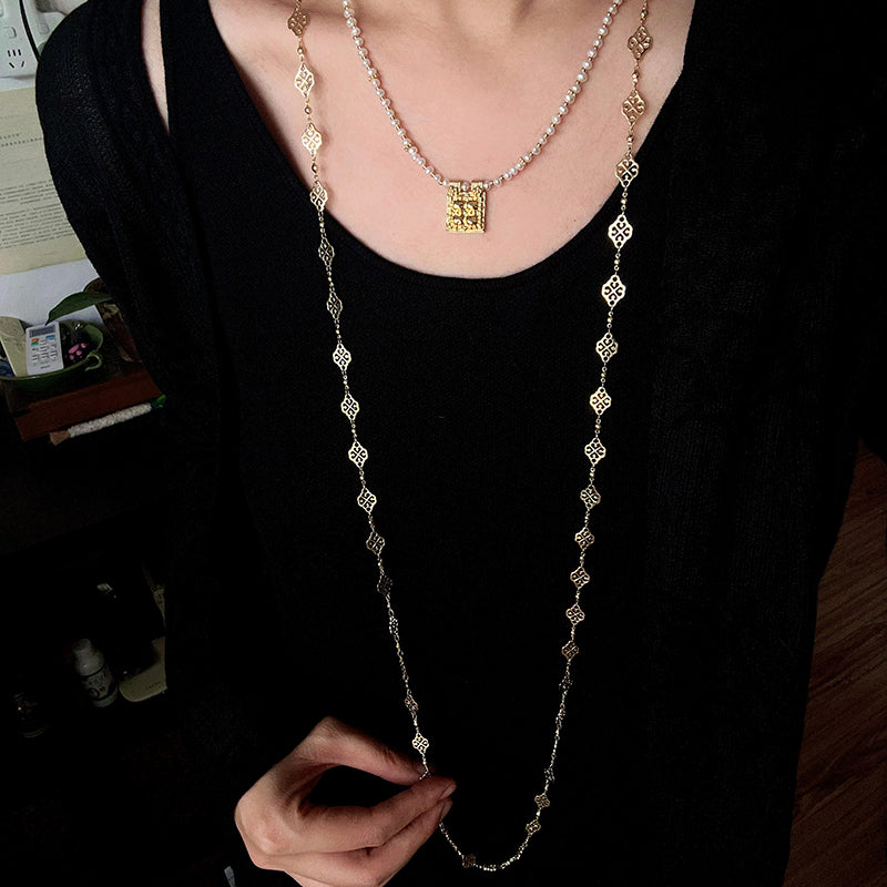 Square pendant necklace layered with longer necklaces