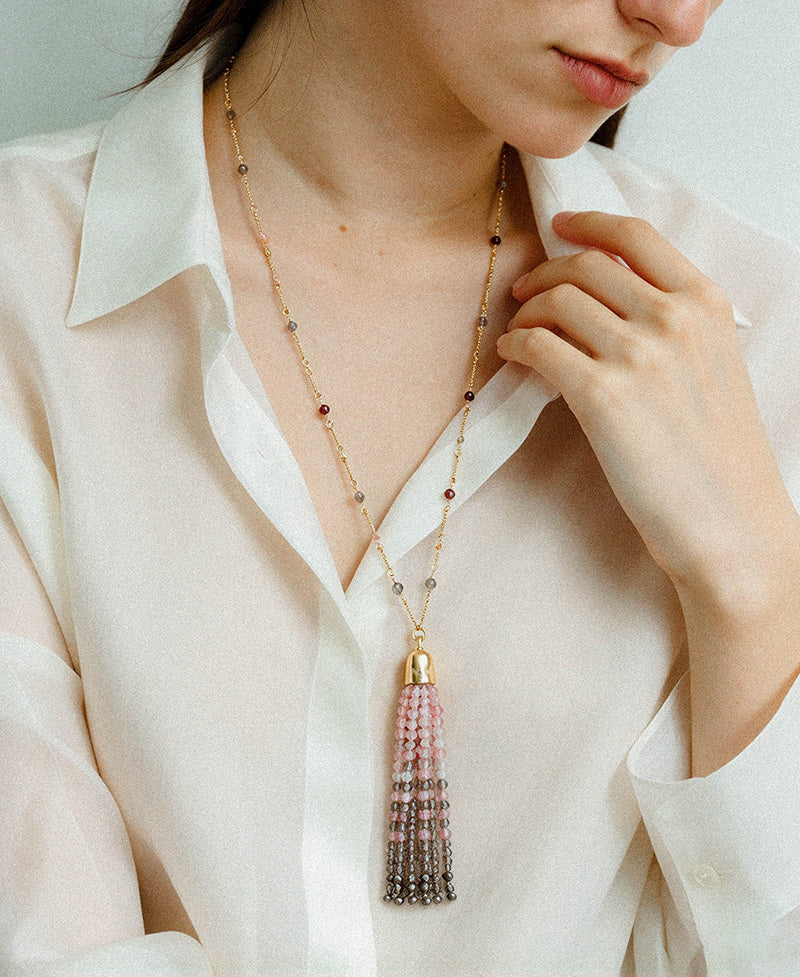 Close-up of pink and grey gemstone tassel necklace styled with a white shirt